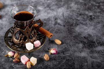 A glass of tea, pistachios, turkish lokum and cinnamon on a blue marble