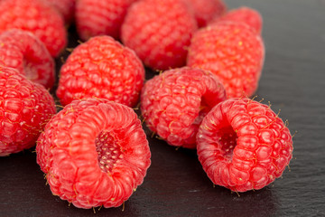 fresh red raspberry fruits on black slate plate