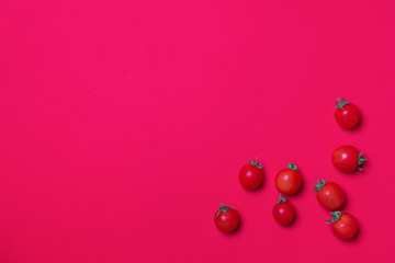 small group of red tomato in left corner of red colored paper background with copy space