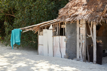 A shack built of boards and reeds on a sandy beach on a sunny day.