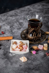 Pistachios, sweets and nuts in a white saucer with a glass of tea