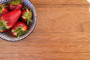 bowl with strawberries on wooden background