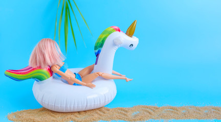 Creative composition of a doll with pink hair and  swan unicorn inflatable toy, the concept of...