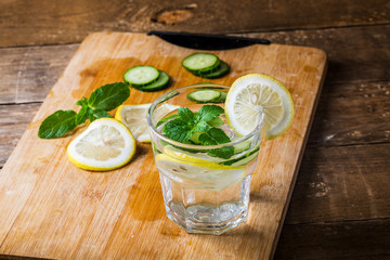 Fresh water with lemon, mint and cucumber on wooden background