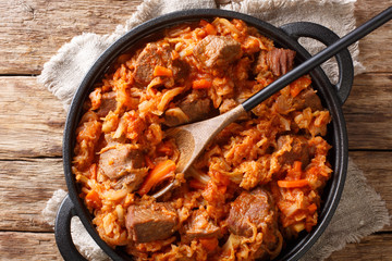 Traditional cabbage stew with meat, tomatoes, carrots and onions close-up in a pan. Horizontal top...