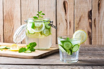 Fresh water with lemon, mint and cucumber on wooden table