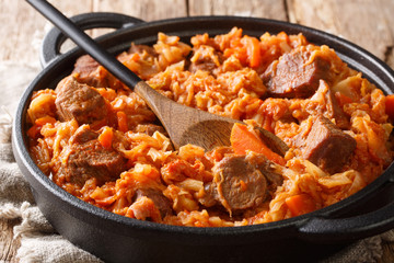 Traditional cabbage stew with meat, tomatoes, carrots and onions close-up in a pan. horizontal