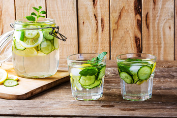 Fresh water with lemon, mint and cucumber on wooden table