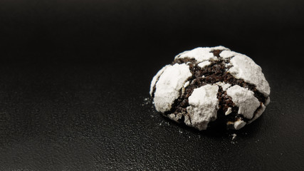 Homemade chocolate cookies. Chocolate brownie cookies in powdered sugar in black background. Selective focus.