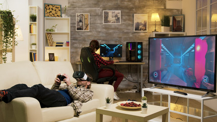 Man lying on sofa playing video games using vr headset