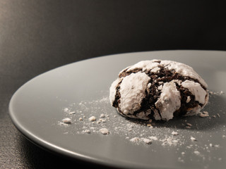 Homemade chocolate cookies. Chocolate brownie cookies in powdered sugar in black background. Selective focus.