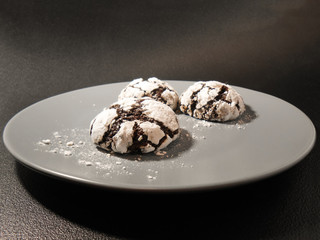Homemade chocolate cookies. Chocolate brownie cookies in powdered sugar in black background....