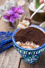 Homemade tiramisu in a pot on a wooden table 