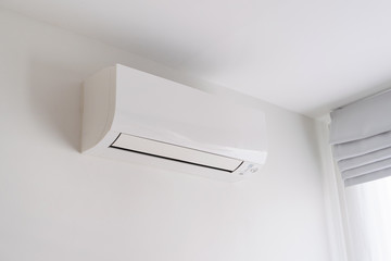 Air conditioner on white concrete wall in room space.