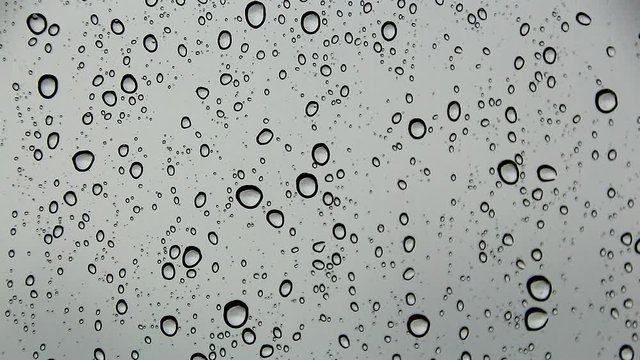 Water beads and Water droplets flowing and moving on the background dark gray glass