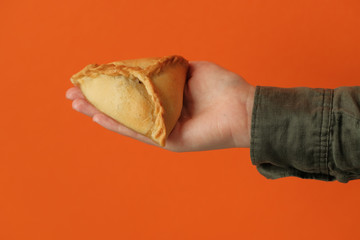 Echpochmak Tatar traditional dish. Echpochmak in hand on an orange background. Traditional food, quick snack of dough. 