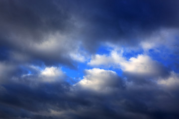 Dark gray dramatic sky with large clouds and sunlight.