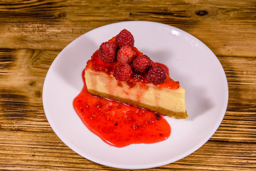 White plate with cheesecake New York and raspberries on wooden table