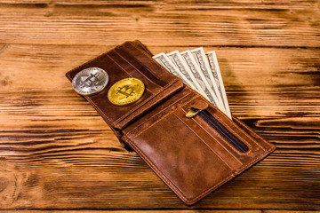 Brown leather wallet, bitcoins and one hundred dollar banknotes on the wooden background