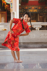 Asian child girl smiling and snaughty in the temple, Concept costume Chinese new year