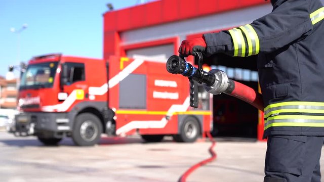 A fireman keeps fire hose for training. Slow motion and close up shot. Fire station background.