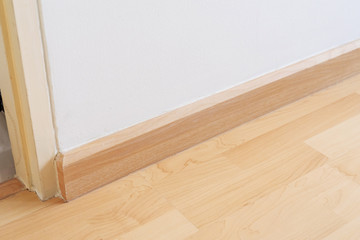 Naklejka na ściany i meble Wooden wall base skirting, finishing material with wood laminate floor and white mortar wall. Empty room with white wall and wooden floor.