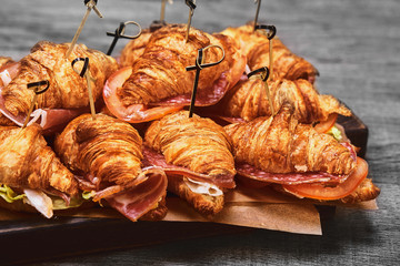 A large set of many croissants with different fillings laid out on a table on a gray background. Seth fast food. Gray background, copy space.