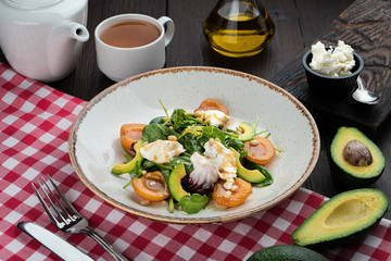 Gourmet salad with apricot, spinach, goat cream cheese and avocado on a covered table in italian restaurant