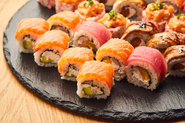 Various kinds of sushi roll set served on black stone. Japanese food