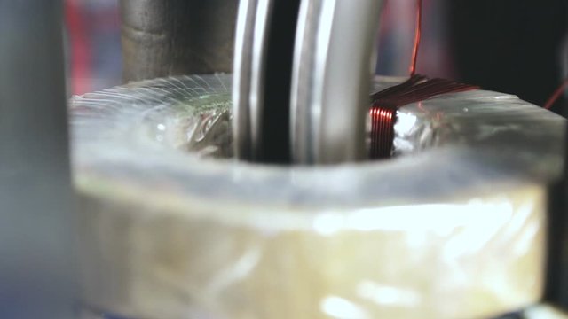 The hands of a specialist controls the production process of the transformer. Transformer coil in the manufacturing process.