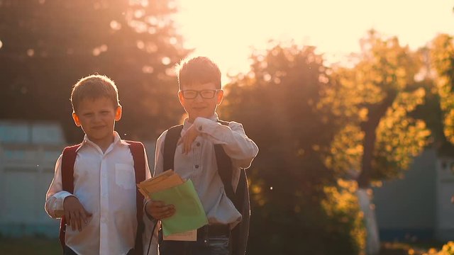 CU, Slow motion: school kids in school uniform with bags hold books and paper sheets wave hands to repel mosquitoes at back sunlight
