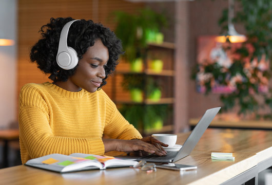 Young woman having online training, using laptop and wireless headset