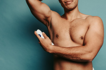 Cut view of muscled strong man's body. Young arabian guy using spray deodorant. Advertisement....