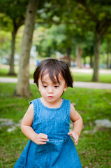 Asian 1 year old toddler is busy playing in a tropical park in the morning.