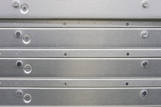 Background of a metal surface made of plates connected by screws, close-up copy space