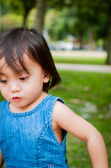 Asian 1 year old toddler is busy playing in a tropical park in the morning.