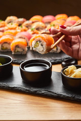 Hand with chopsticks soaks sushi in soy sauce. Tasting Japanese food.