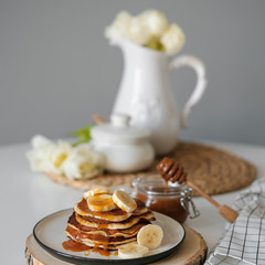 delicious American pancakes with bananas and honey on the plate for a breakfast. selective focus. Scandinavian style kitchen. 