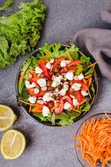 A salad of fresh lettuce leaves, tomato,mozzarella, carrots and hazelnut with olive oil and juice lemon in a ceramic plate
