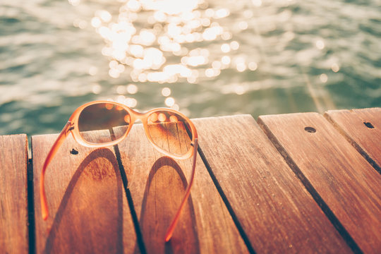 Sunglasses at the wooden pier during sunset. Luxury vacation resort. Holiday getaway concept. Horizontal, warm toning
