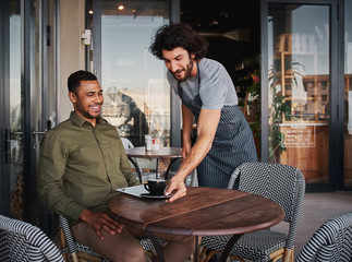 Cheerful young man serving afro-american customer at coffee shop