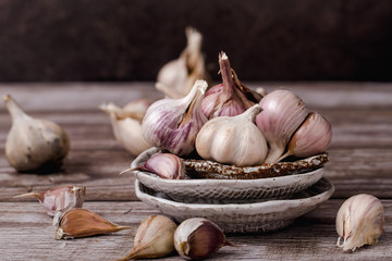 The bulbs of garlic, slice, on ceramic plate on a wooden table, horizontal format