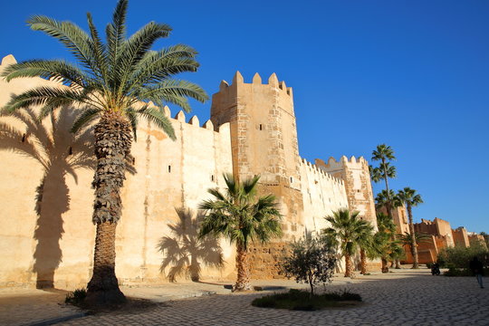The impressive ramparts of the medina surrounded by colorful palmtrees and a large cobbled walkway in Sfax, Tunisia