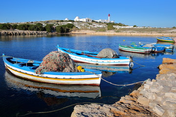 The old Fatimid port of Mahdia, Tunisia, with colorful fishing boats and the mosque lighthouse in...