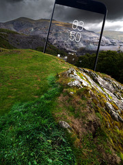 A montage with a beautiful mountain landscape seen by a mobile phone