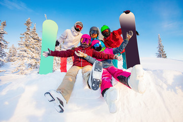 Happy team of friends skiers and snowboarders hugging and having fun in fresh snow in winter forest