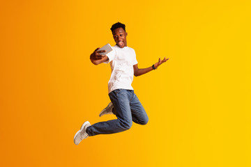 Fototapeta na wymiar Handsome african guy making selfie while jumping