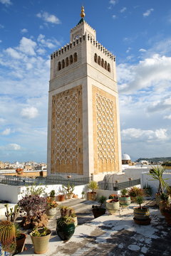 The ornate patterned minaret of Ez Zitouna Mosque (Great Mosque) viewed from a terrace in Tunis, Tunisia, with colorful plants in the foreground