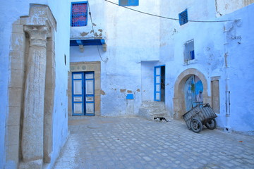 Typical cobbled and narrow street  inside the historical medina of Kairouan in Tunisia, with blue...