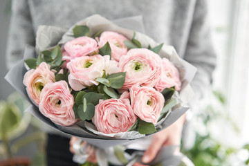 Bunch pale pink ranunculus flowers with green eucalyptus. The work of the florist at a flower shop.